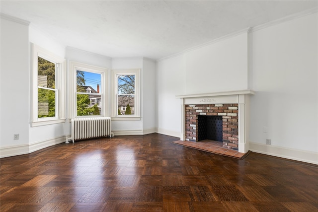 unfurnished living room with ornamental molding, radiator, and a brick fireplace