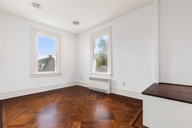 unfurnished room with baseboards, a healthy amount of sunlight, and radiator heating unit
