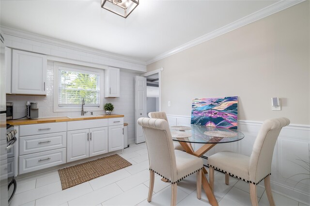645 Hawkins Blvd, Copiague, NY 11726 - kitchen featuring stove, butcher block countertops, ornamental molding, a sink, and wainscoting