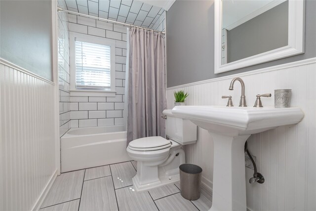 645 Hawkins Blvd, Copiague, NY 11726 - bathroom featuring a wainscoted wall, shower / bath combo with shower curtain, a sink, and toilet