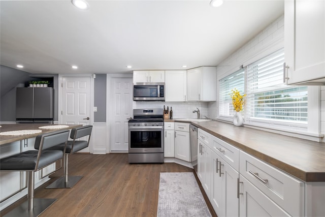 645 Hawkins Blvd, Copiague, NY 11726 - kitchen with white cabinetry, stainless steel appliances, dark wood-style floors, and butcher block counters