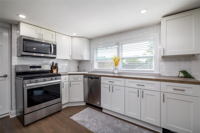 645 Hawkins Blvd, Copiague, NY 11726 - kitchen featuring wooden counters, dark wood finished floors, tasteful backsplash, appliances with stainless steel finishes, and white cabinetry