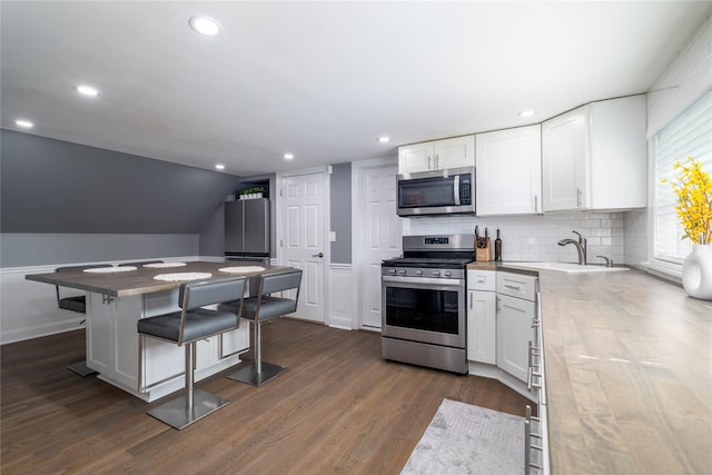 645 Hawkins Blvd, Copiague, NY 11726 - kitchen featuring a kitchen bar, appliances with stainless steel finishes, dark wood-type flooring, white cabinetry, and a sink