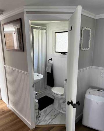 12 Bluebird Dr, Lake Luzerne, NY 12846 - bathroom featuring a wainscoted wall, ornamental molding, curtained shower, and wood finished floors