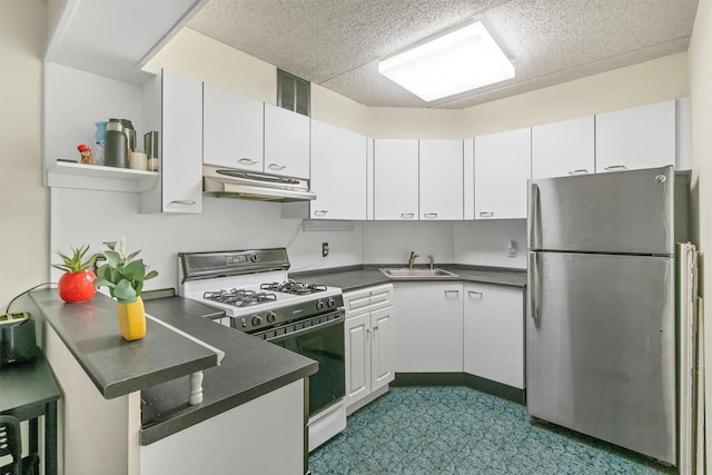 kitchen with under cabinet range hood, a sink, freestanding refrigerator, a peninsula, and white range with gas stovetop