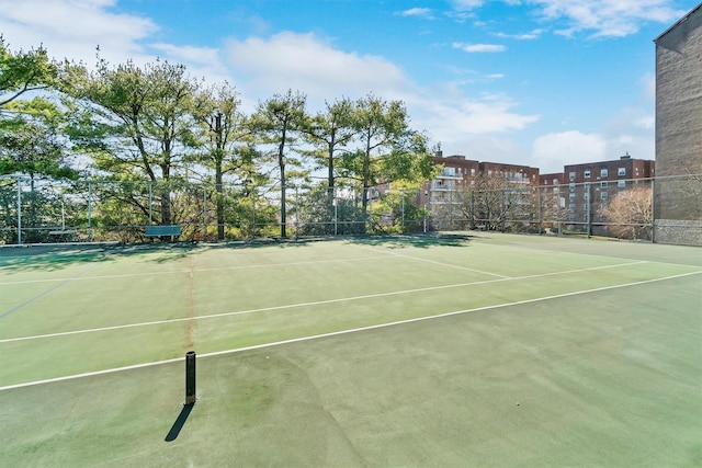 view of tennis court with community basketball court and fence