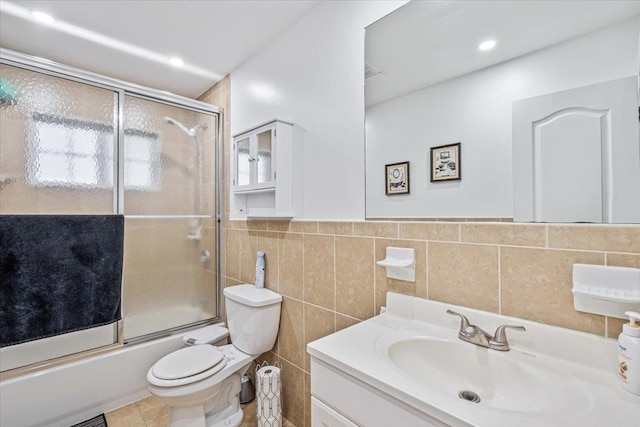 full bath with toilet, vanity, enclosed tub / shower combo, tile patterned flooring, and tile walls