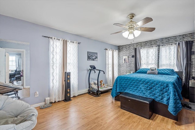 bedroom with baseboards, light wood-style flooring, and a ceiling fan