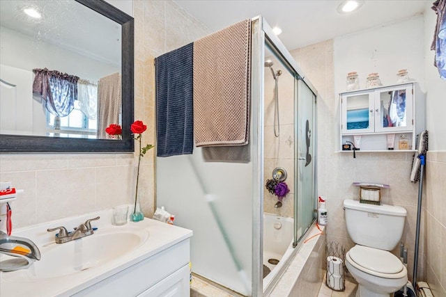 full bathroom with tile walls, bath / shower combo with glass door, a baseboard radiator, toilet, and vanity