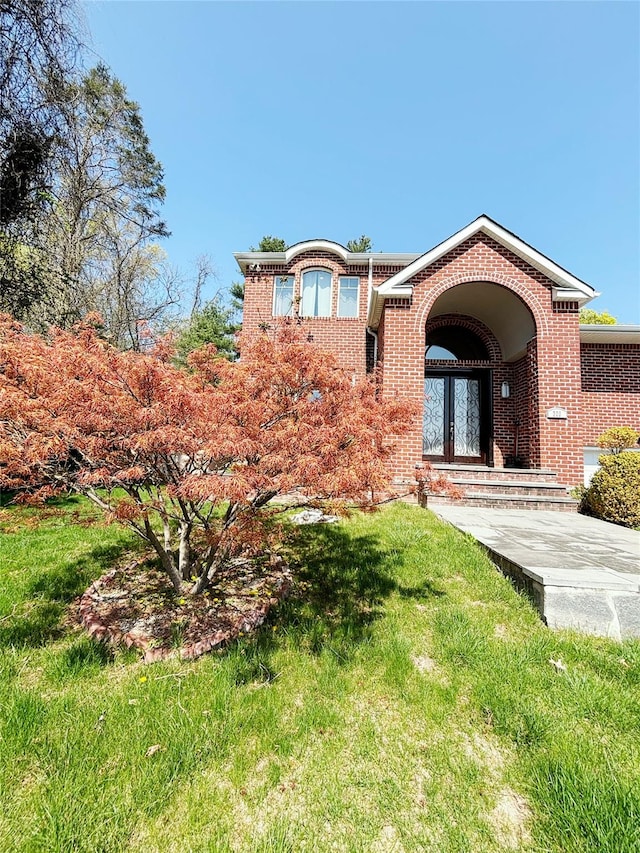 300 Ellen Pl, Oyster Bay, NY 11753 - view of front facade with brick siding, french doors, and a front yard