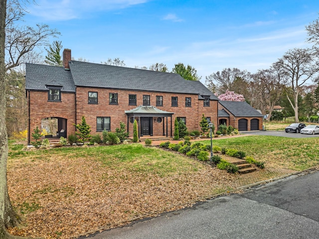 28 Northfield Rd, Glen Cove, NY 11542 - view of front of property with roof with shingles, brick siding, driveway, a front lawn, and a chimney
