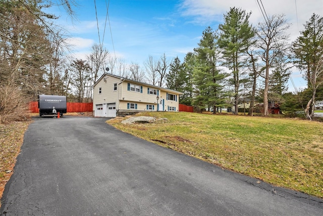 view of front of house featuring an attached garage, a front lawn, and aphalt driveway
