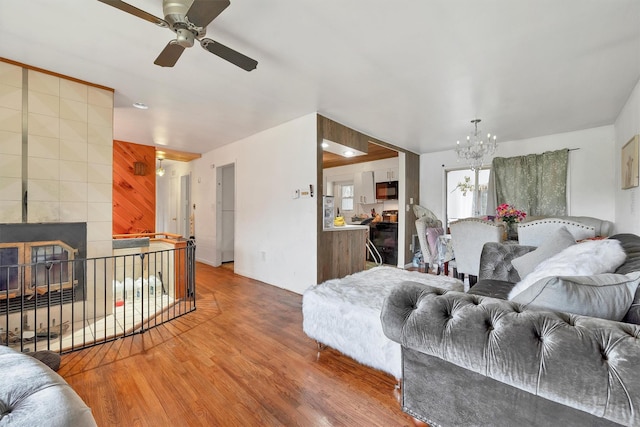 living room featuring wood finished floors and ceiling fan with notable chandelier