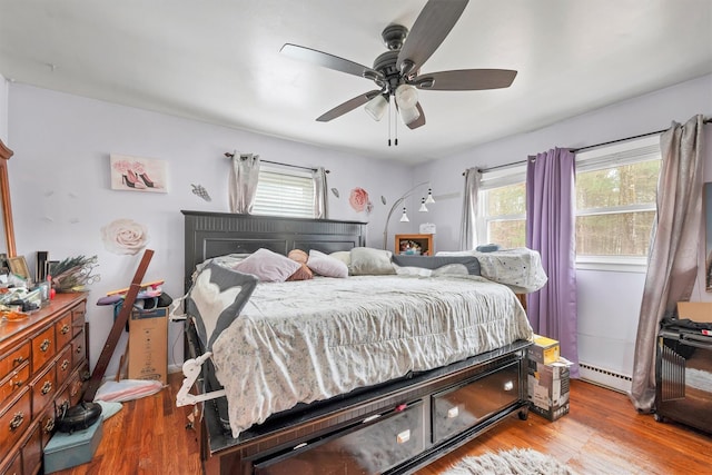 bedroom with wood finished floors, a ceiling fan, and baseboard heating