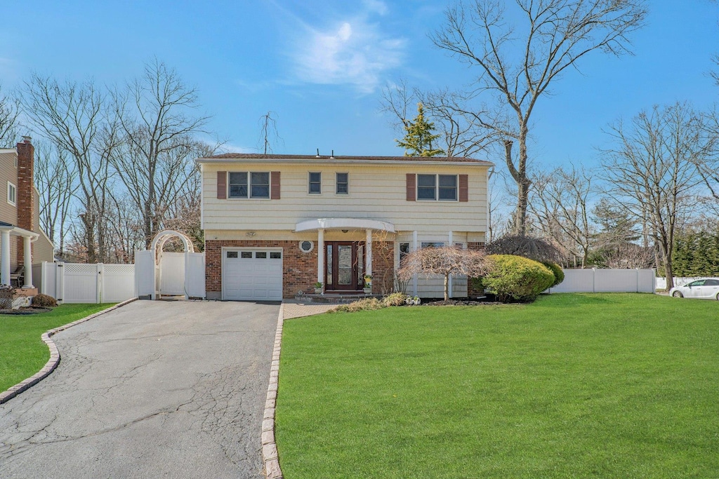 view of front of property with driveway, a gate, fence, and a front yard