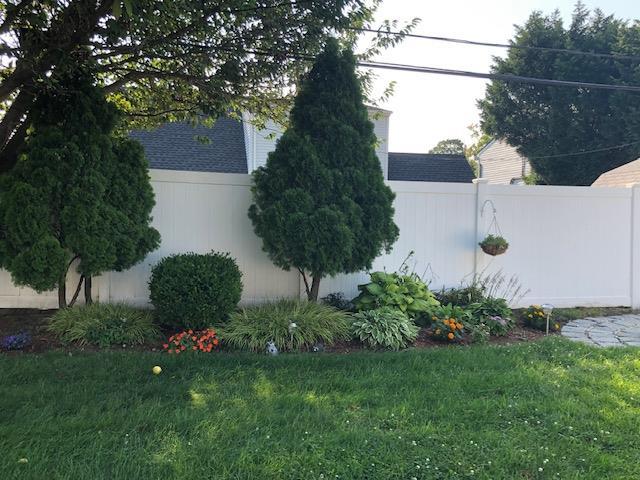 view of side of property with a yard, fence, and a shingled roof