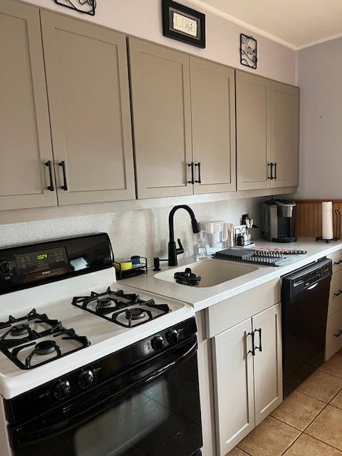 kitchen featuring light tile patterned floors, gas range, dishwasher, a sink, and light countertops