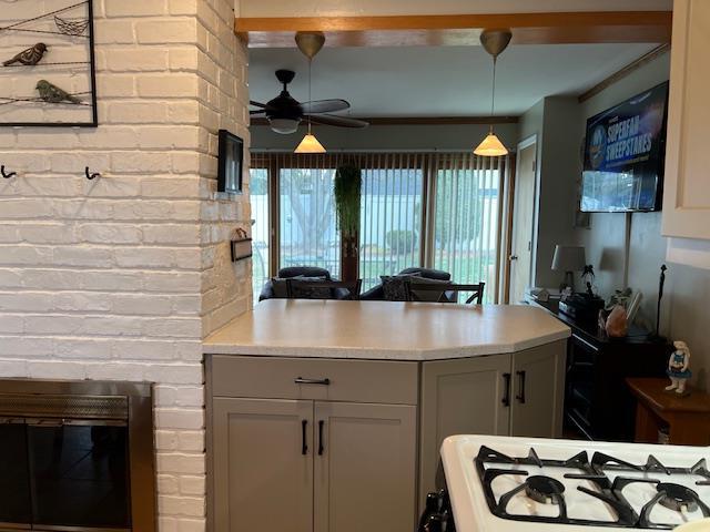 kitchen featuring gray cabinets, ceiling fan, light countertops, and white gas range oven