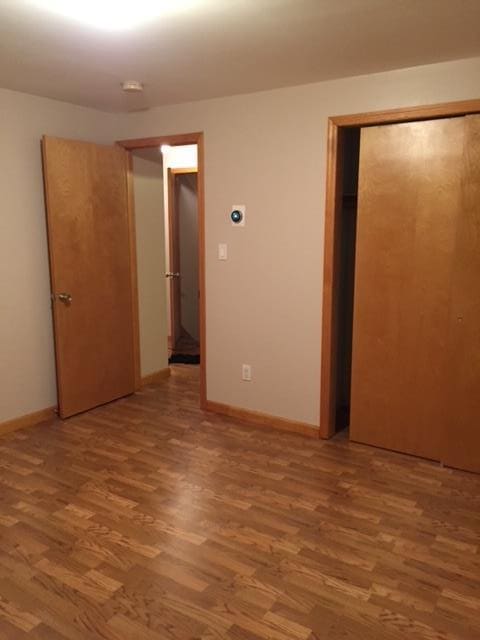unfurnished bedroom with a closet, baseboards, and light wood finished floors