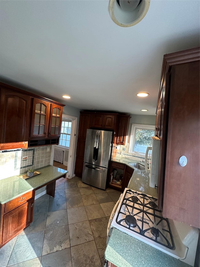 kitchen with gas range, backsplash, plenty of natural light, and freestanding refrigerator