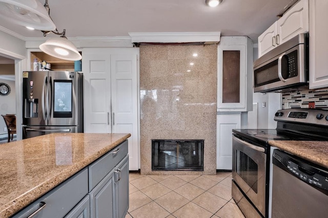 63 Bucket Ln, Levittown, NY 11756 - kitchen featuring crown molding, light tile patterned flooring, a glass covered fireplace, backsplash, and appliances with stainless steel finishes