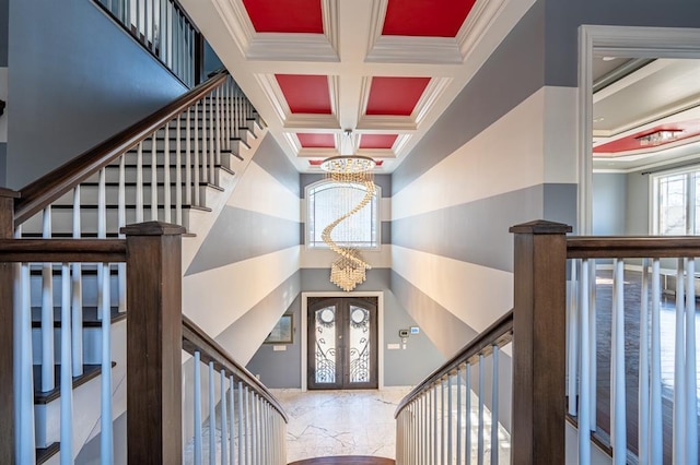 entrance foyer featuring coffered ceiling, a notable chandelier, ornamental molding, and french doors
