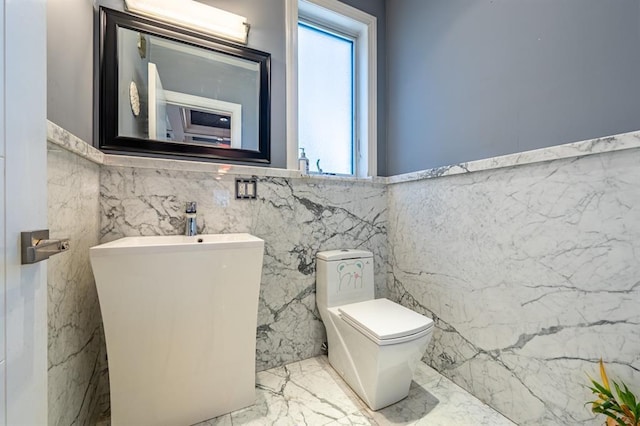half bathroom featuring marble finish floor, plenty of natural light, and toilet