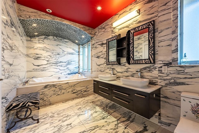 full bathroom featuring stone wall, double vanity, a sink, and a bath