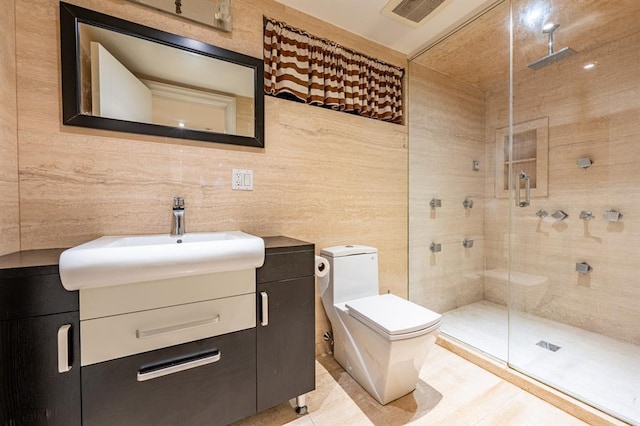 bathroom with tile walls, visible vents, toilet, vanity, and a stall shower