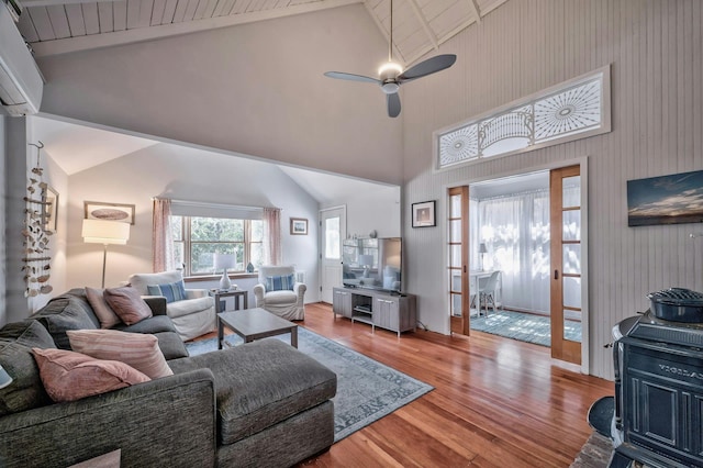 living room featuring a wall mounted AC, wood finished floors, ceiling fan, and high vaulted ceiling