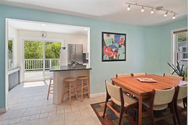 dining area featuring baseboards, rail lighting, and light tile patterned floors