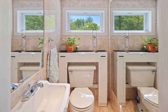 bathroom with toilet, tile walls, and a wealth of natural light
