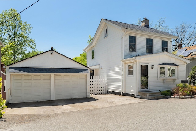 traditional-style house with a garage, fence, an outbuilding, and a chimney