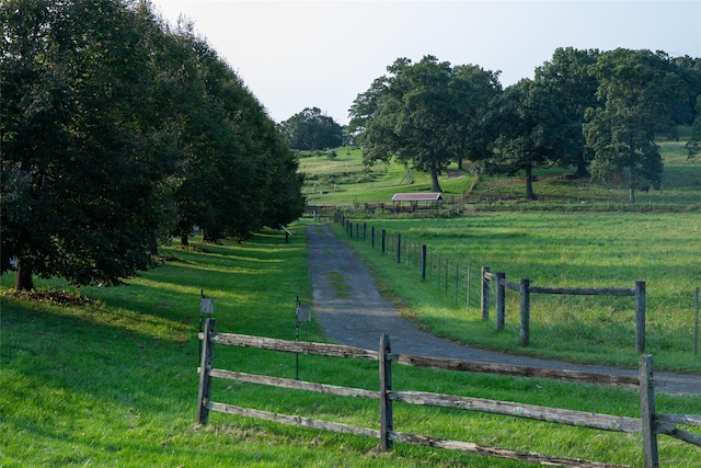 surrounding community with a yard, a rural view, and fence