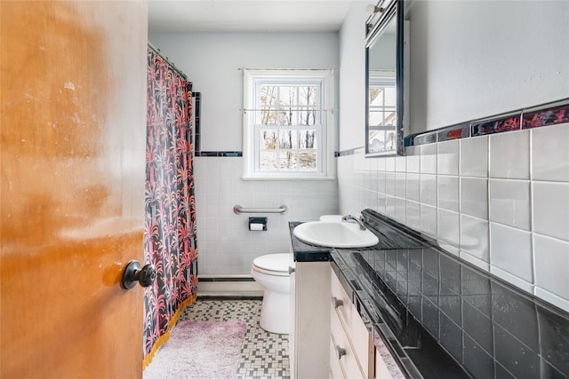 full bath featuring a wainscoted wall, baseboard heating, toilet, tile walls, and vanity