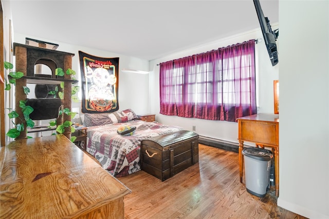 bedroom with wood finished floors and a baseboard radiator