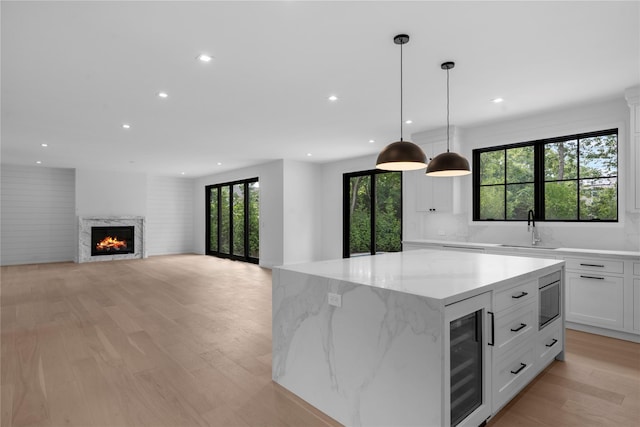 466 Montauk Hwy, Westhampton Beach, NY 11978 - kitchen featuring wine cooler, a kitchen island, recessed lighting, light wood-style flooring, and white cabinetry