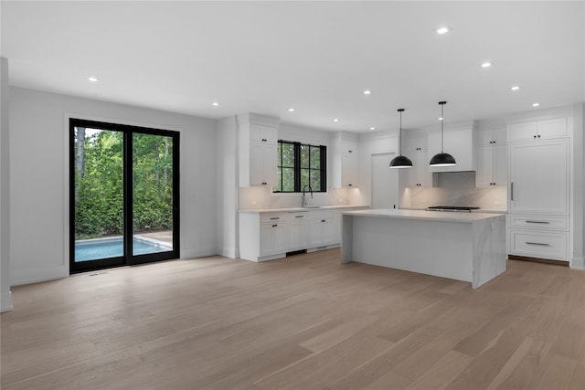 466 Montauk Hwy, Westhampton Beach, NY 11978 - kitchen featuring tasteful backsplash, light wood-style flooring, white cabinets, light countertops, and healthy amount of natural light