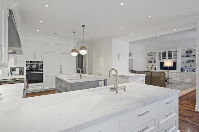 24 Penwood Rd, Bedford Corners, NY 10549 - kitchen featuring dark wood-type flooring, an island with sink, a sink, and wall chimney exhaust hood