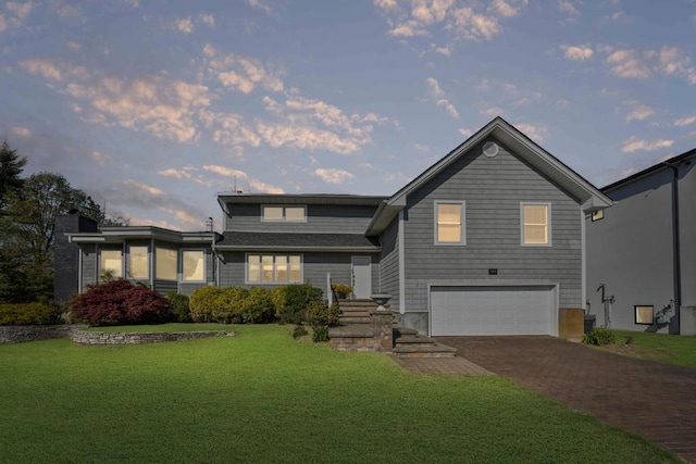 view of front of house featuring an attached garage, a front lawn, and decorative driveway
