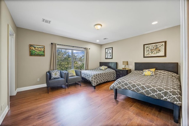 bedroom with wood finished floors, visible vents, and baseboards