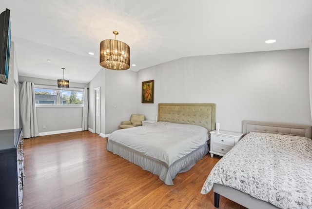 bedroom with lofted ceiling, a notable chandelier, baseboards, and wood finished floors