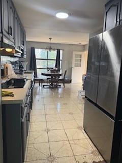 kitchen featuring black appliances, light countertops, light tile patterned floors, and a chandelier