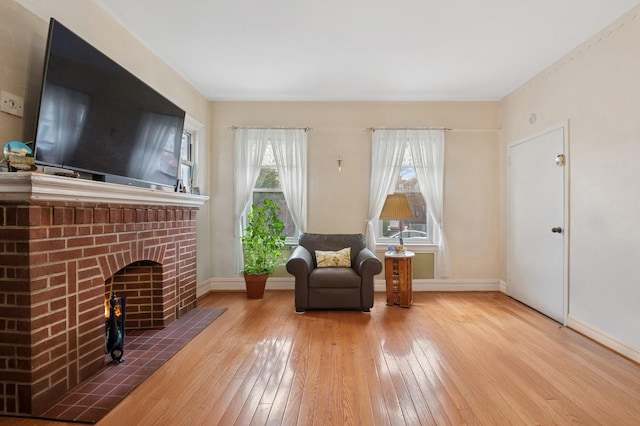 sitting room with a fireplace, baseboards, and hardwood / wood-style flooring