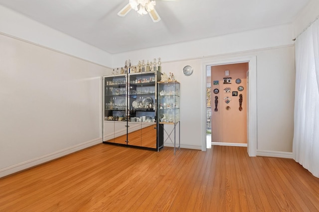 unfurnished room with baseboards, a ceiling fan, and wood finished floors