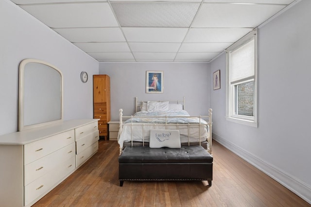 bedroom with a paneled ceiling, baseboards, and hardwood / wood-style floors