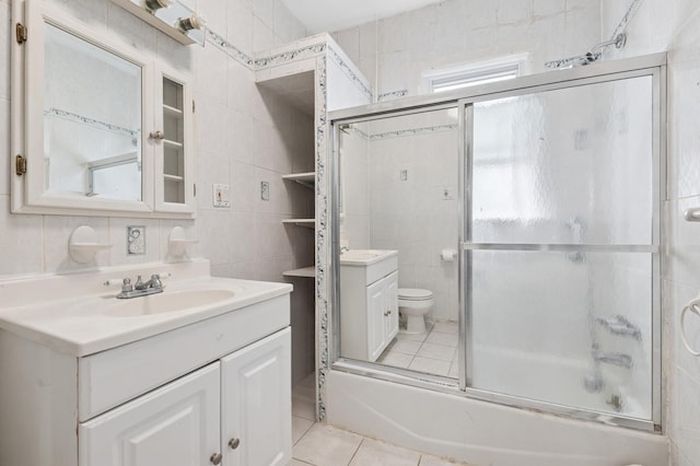 bathroom with toilet, tile patterned floors, vanity, and tile walls