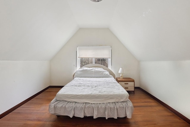 bedroom with lofted ceiling, baseboards, and wood finished floors