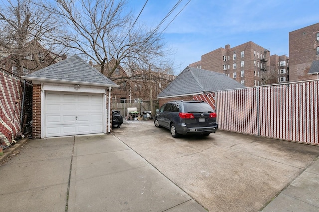 detached garage featuring driveway and fence