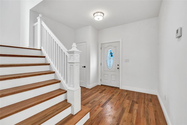 foyer with baseboards, stairs, and wood finished floors